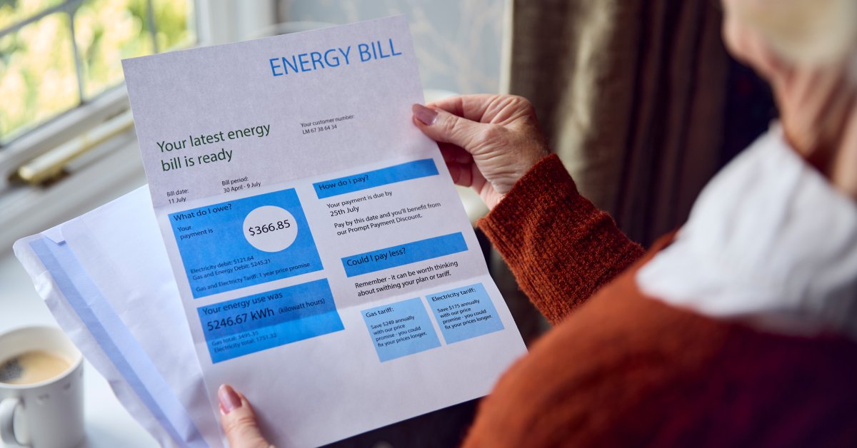A person is holding an energy bill. It says, "Your latest energy bill is ready," with an amount of "$366.85."