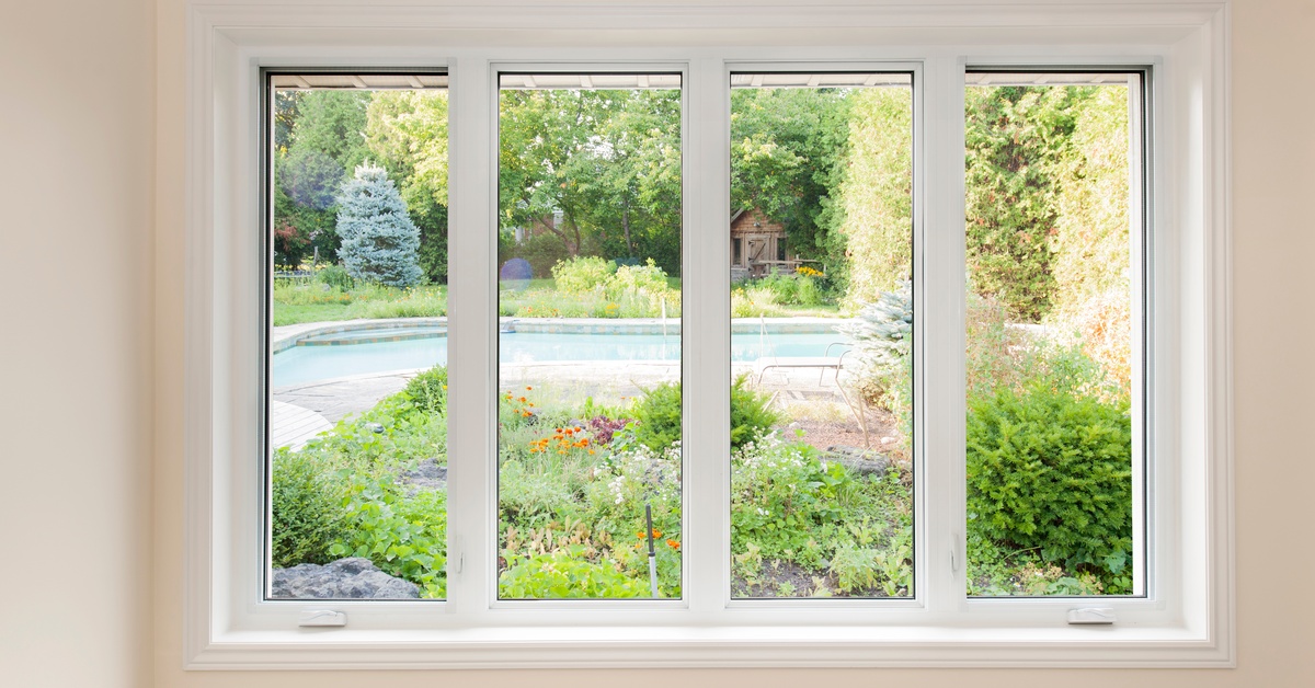 A white-framed window offers a view of a lush backyard with a swimming pool, vibrant greenery, flowers, and a small shed.