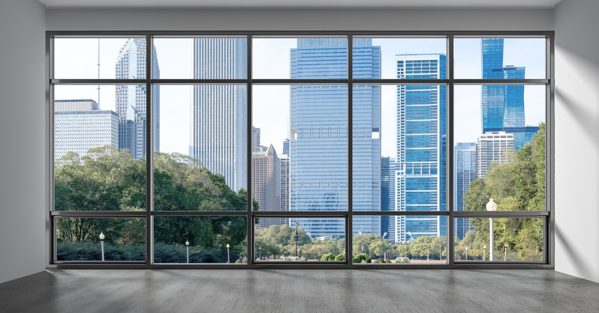 A large window with a black frame shows a view of Chicago's downtown skyline and trees on a sunny day.